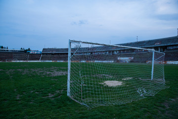 Fototapeta premium Abadoned Stadion Za Luzankami is a currently inactive stadium in Brno, Czech Republic. Captured in spring sunset, sky and clouds was colored to blue dark colors. Photo from tribunes and inside middle