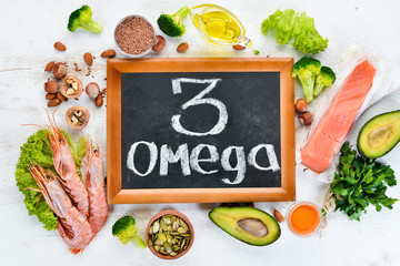 Foods containing omega 3. Vitamin Healthy foods: avocados, fish, shrimp, broccoli, flax, nuts, eggs, parsley. Top view. Free space for your text. On a white wooden background. - obrazy, fototapety, plakaty