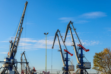 Fototapeta na wymiar Large iron port crane while working on blue sky background.