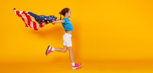 Fototapeta na wymiar happy child girl with flag of United States of America USA on yellow background