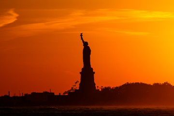 statue of liberty at sunset with silhouette and orange sky