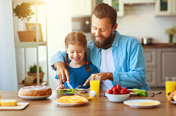 happy family father with child  feeds his   daughter in kitchen with Breakfast