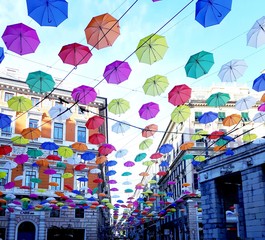 Fototapeta na wymiar Genova, Italy - 06/01/2019: Bright abstract background of jumble of rainbow colored umbrellas over the city celebrating gay pride