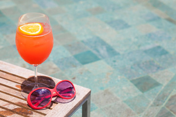 exotic cocktail and sunglasses by the pool of a luxury hotel