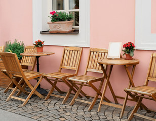 Outdoor cafe empty tables with flowers along a Prague cobblestone street.