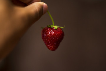 in the twilight a man is sexually holding strawberries in his hand