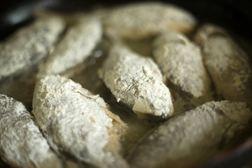 small crucian carp in flour fried in a pan