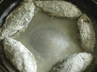small crucian carp in flour fried in a pan