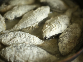 small crucian carp in flour fried in a pan