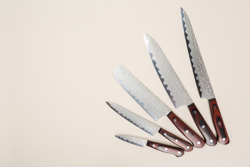 Several different used stainless steel kitchen knives with brown wooden handles