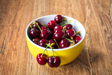 Fresh organic sweet cherries in a glass bowl on wooden table