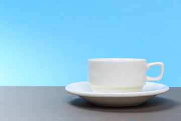 vintage white porcelain tea cup on gray board and blue background