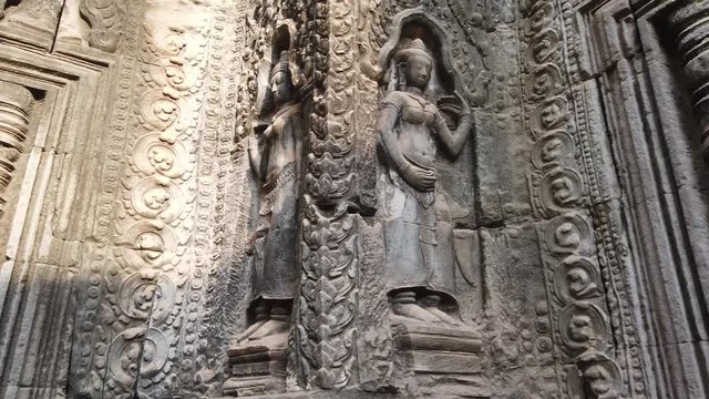 ancient bas-reliefs depicting the divine dancer Apsara in the temple of TA Prohm. One of the most famous temples of Angkor, TA Prohm is known for its huge trees and roots growing from its walls. 
