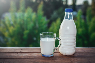 bottle of milk on wooden table with nature background