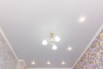 Stretch ceiling in the room with a chandelier and spotlights