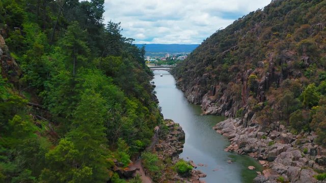 Drone shot over the river between the mountains. A boat is coming. Zic Zag Reserve, Tasamania.