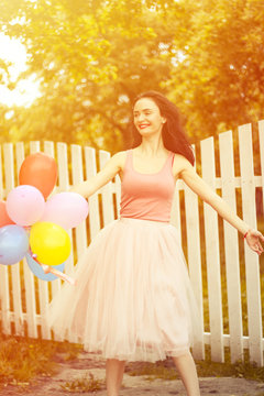  girl running and jumping on summer field with colorful air balloons over sunset . girl running and jumping on summer field with colorful air balloons over Sunset 