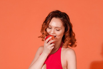 the girl biting the Apple on a red background