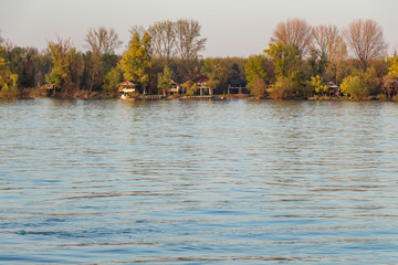 Small bungalows on the river front. Peaceful nature scenery. Golden hour.
