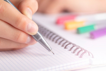 Teen writes black yellow pen in a checkered notebook