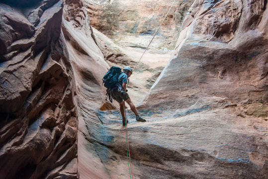 USA, Utah, Moab, Canyoneering, Man rappelling down in slot canyon