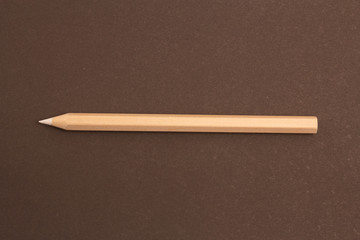 White pencil lies diagonally on a black background