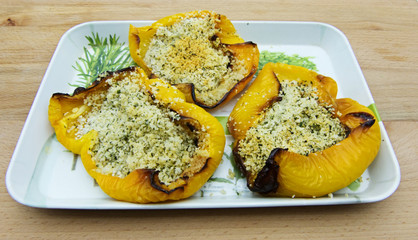 Baked yellow peppers stuffed with bread and olive oil, on wooden table