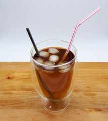 Iced tea with red and blue straw on wooden table, white background