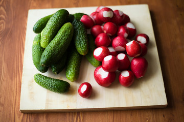 small cucumbers and fresh red radish background close-up