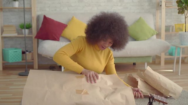 portrait african woman with an afro hairstyle unpacks a new guitar