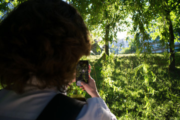 Woman using smartphone to capture beautiful sunset in park