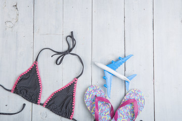 Travel and vacation concept - model of airplane, fashion swimsuit with flip flops in polka dots