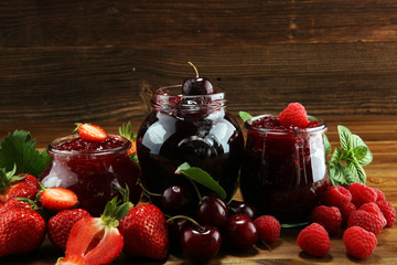 assortment of jams, seasonal berries, cherry, mint and fruits in glass jar