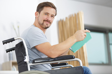 physically handicapped man in wheelchair with book