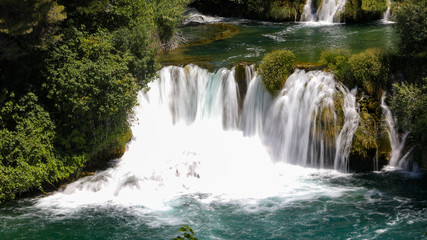 Obraz premium Close view to the waterfall in the mountain lake in the national park of Croatia in summer