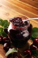 Rustic jar with cherry jam and fresh cherries, homemade preserves on wood