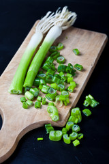 Fresh green organic chopped onions on a cutting board.