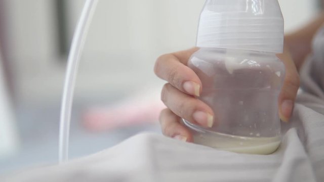 Young mother using electric breast pump pumping breast milk feeding for her baby.