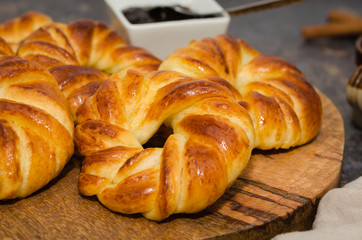 Sweet fresh baked buns served with jam on rustic wooden board 