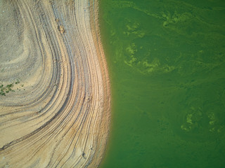 Aerial view of the Valdecañas reservoir, with green water from the algae and natural lines of the...
