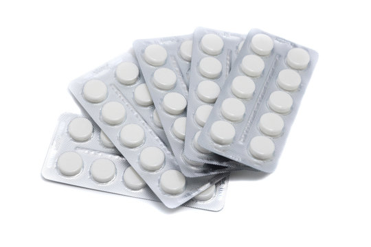 white pills in packaging sheets on white background