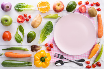Healthy lifestyle and food concept. Top view of fresh vegetables, fruit, herbs and spices with a empty pink pastel plate on white wooden background.