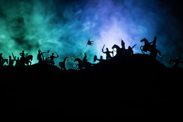 Naklejka na ściany i meble Medieval battle scene with cavalry and infantry. Silhouettes of figures as separate objects, fight between warriors on dark toned foggy background with medieval castle.