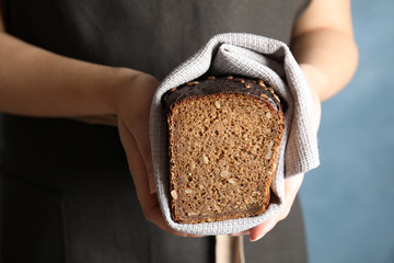 Baker holding cut bread on color background, closeup