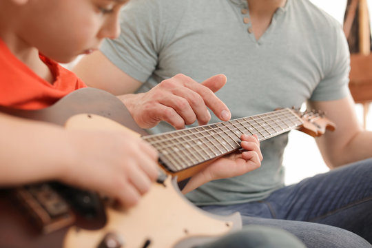 Little boy playing guitar with his teacher at music lesson, closeup. Learning notes - Powered by Adobe