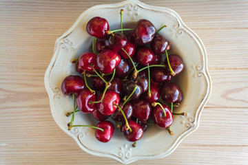 Bowl of cherries on wooden table. Top view