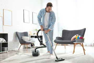 Portrait of janitor with vacuum cleaner in living room