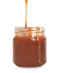 Tasty caramel sauce pouring into jar isolated on white