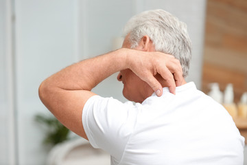 Fototapeta premium Senior man scratching neck indoors. Allergy symptom