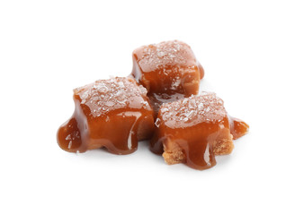 Delicious candies with caramel sauce and salt on white background